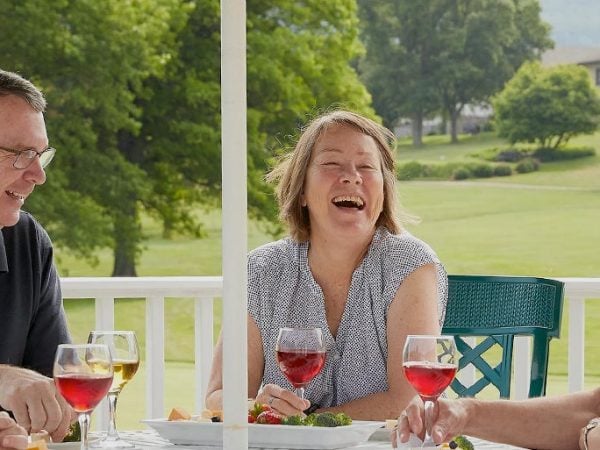 a person laughing while holding a glass of wine